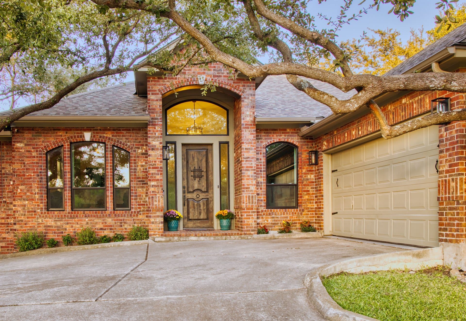Brick home with new arched Anlin windows and rustic wood door completed by Glacier Home Exteriors