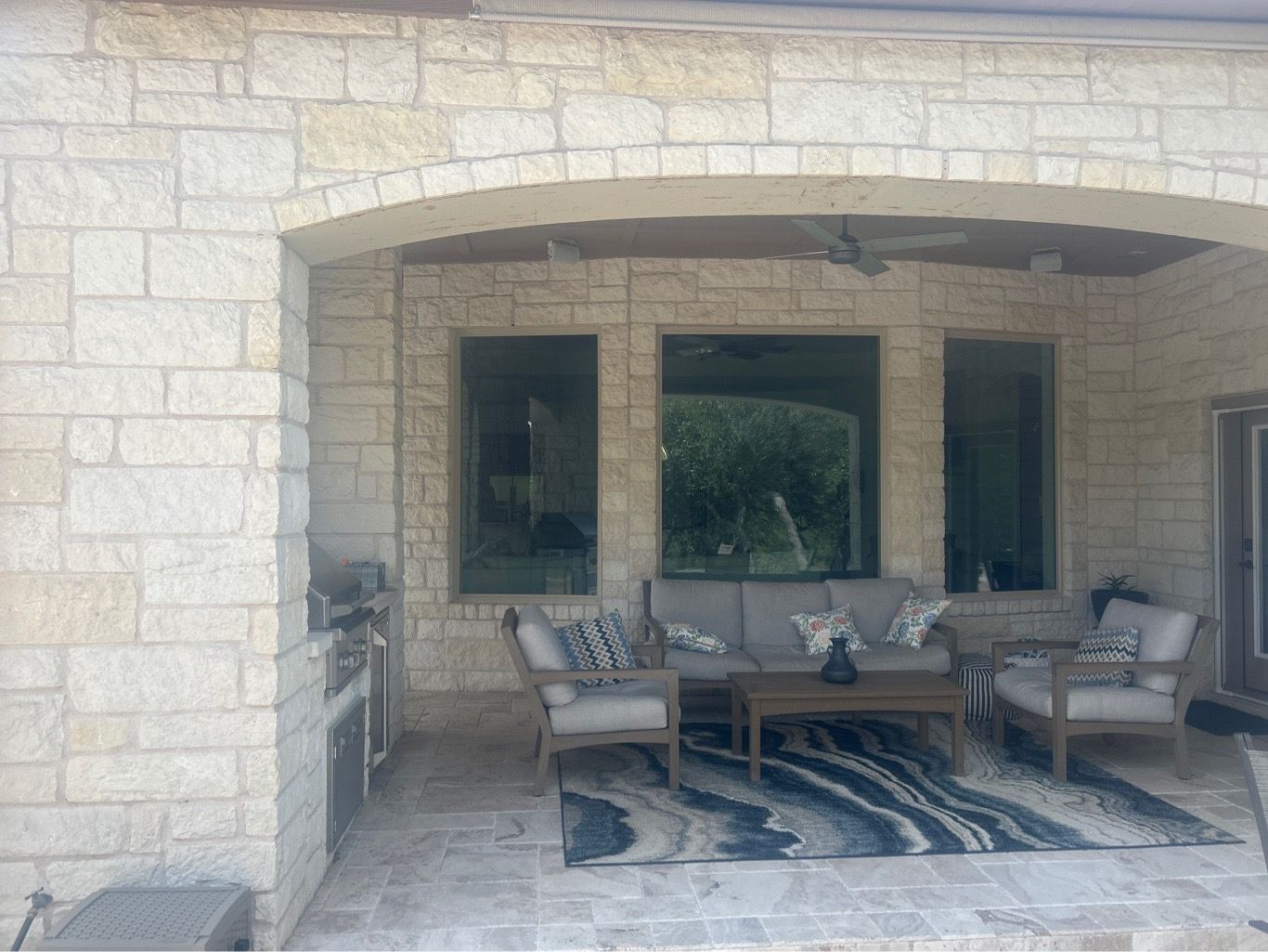 Three Anlin Panoramic windows covered outdoor living room with arched stone entry luxury home Round Rock TX by Glacier Home Exteriors