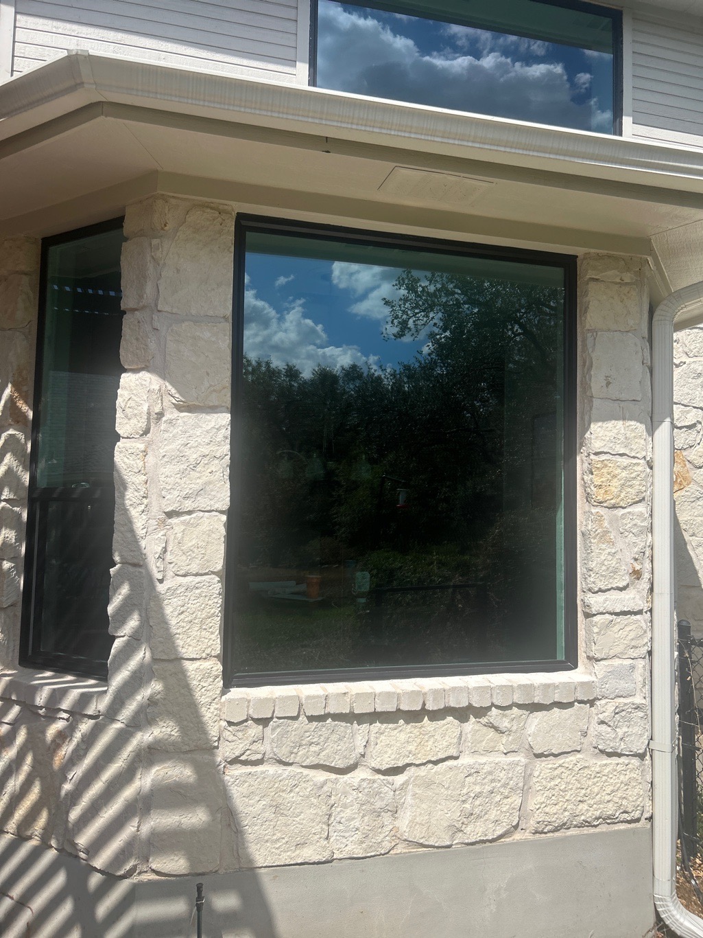 Large Anlin picture window with black frame on cream limestone home Round Rock TX by Glacier Home Exteriors