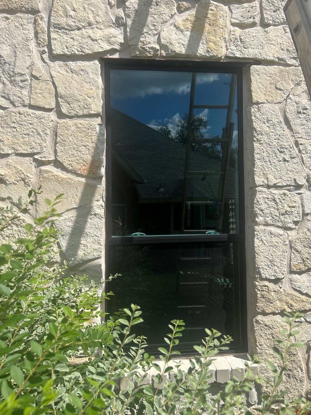 Anlin single-hung window black frame in natural stone masonry wall Round Rock TX by Glacier Home Exteriors